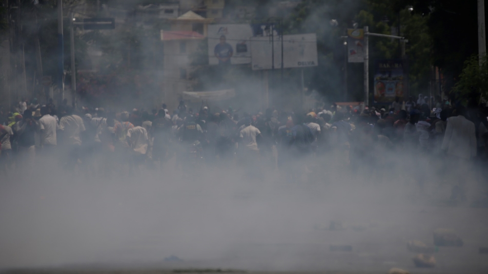 Protesters run away after police fire tear gas during a march called by opposition parties