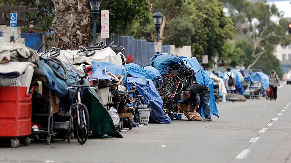 Homeless people stand among their items in San Diego