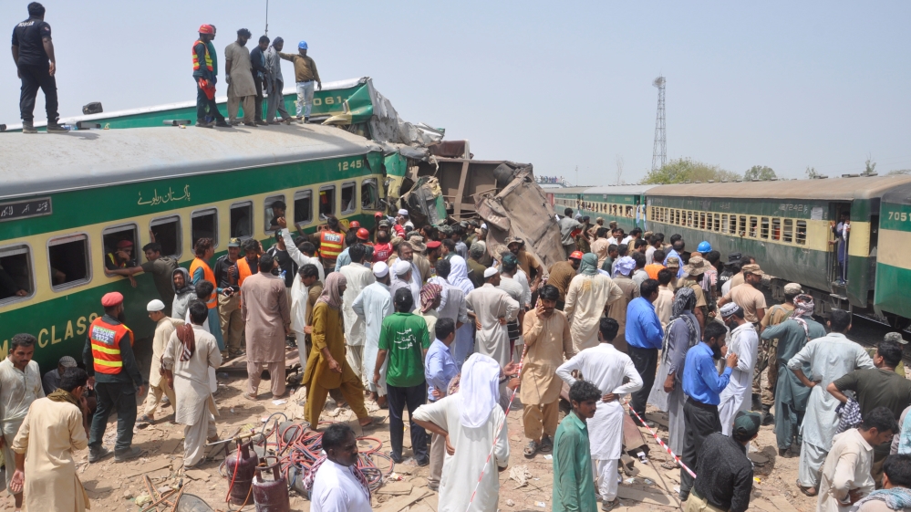 Residents and rescue workers gather near the site after a passenger train collided with a cargo train in Sadiqabad,