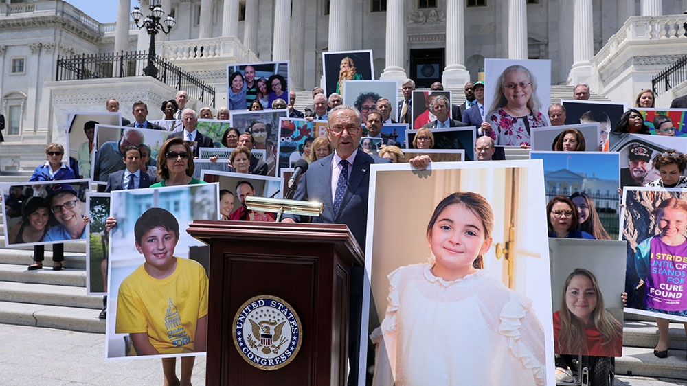 US Senate Minority Leader Chuck Schumer, holding a picture of head-injury victim Emilie Saltzman, and House Speaker Nancy Pelosi lead fellow congressional Democrats for remarks on healthcare coverage of pre-existing conditions, on the steps of the in Washington, DC