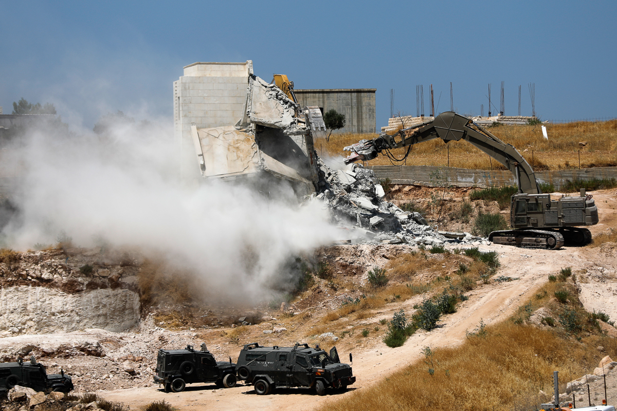 This picture taken from Jerusalem on July 22, 2019 shows Israeli security forces tearing down one of the Palestinian buildings still under construction which have been issued notices to be demolished