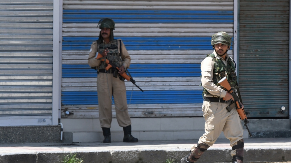 Indian security personnel patrol next to shuttered stores in the Lal Chowk area of Srinagar