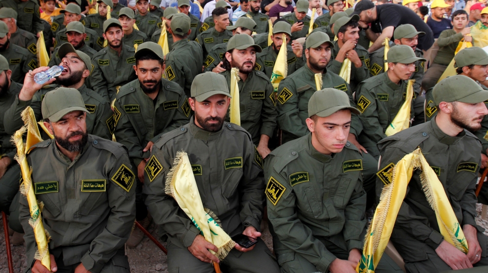 Lebanon’s Hezbollah members hold party flags as they listen to their leader Hassan Nasrallah addressing his supporters via a screen in al-Ain village