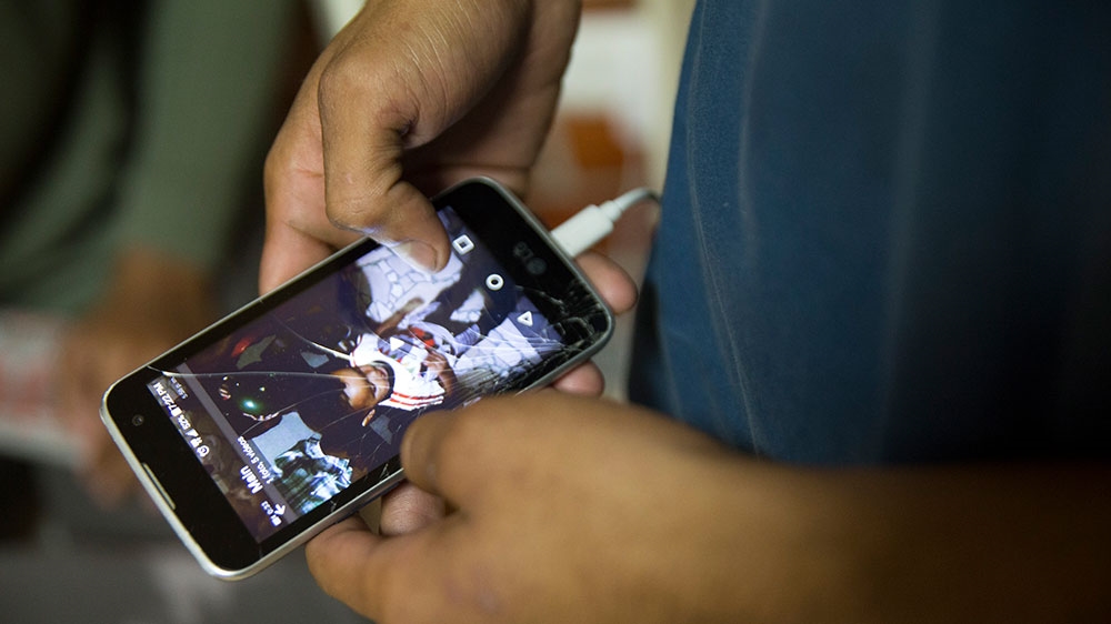 Venezuelan migrant Yonaimer Godoy shows a video of his two-year-old son in Venezuela that his father sent inside a migrant shelter in Lima, Peru