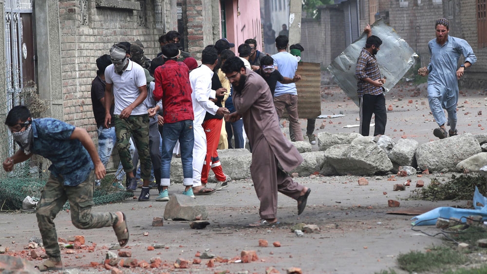 Kashmiris take cover as security forces (unseen) fire tear gas shells during clashes in Srinagar