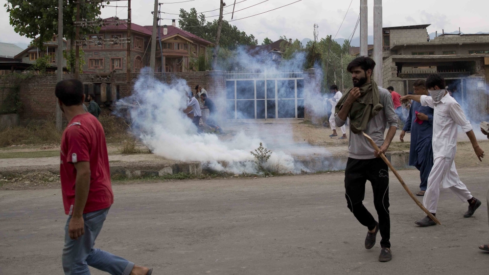 Kashmiris take cover from tear gas shells during a protest after Friday prayers in Srinagar