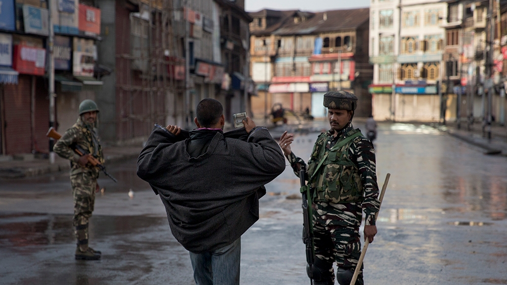 An Indian Paramilitary soldier orders a Kashmiri to lift his robe before frisking him during curfew in Srinagar, Indian controlled Kashmir, Thursday, Aug. 8, 2019. The lives of millions in India''s on