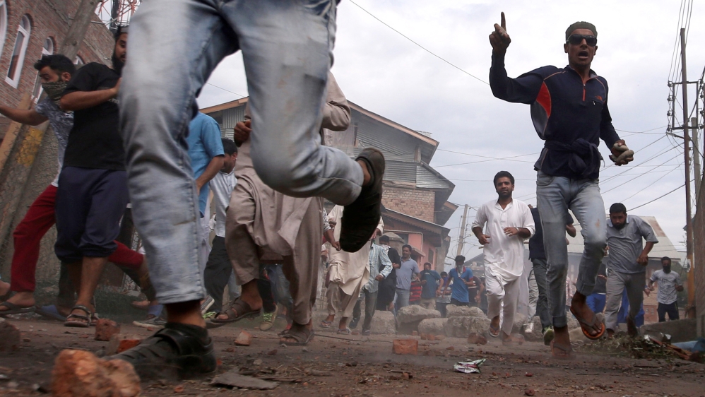 Kashmiris run for cover as Indian security forces (unseen) fire tear gas shells during clashes in Srinagar