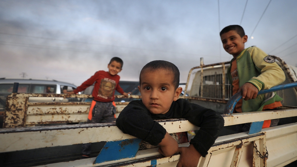 Boys stand on the back of a truck as they flee Ras al Ain town in northeastern Syria.
