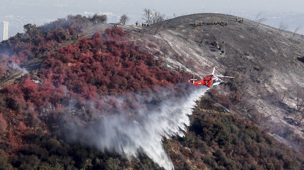 A helicopter drops water on a wildfire in Los Angeles