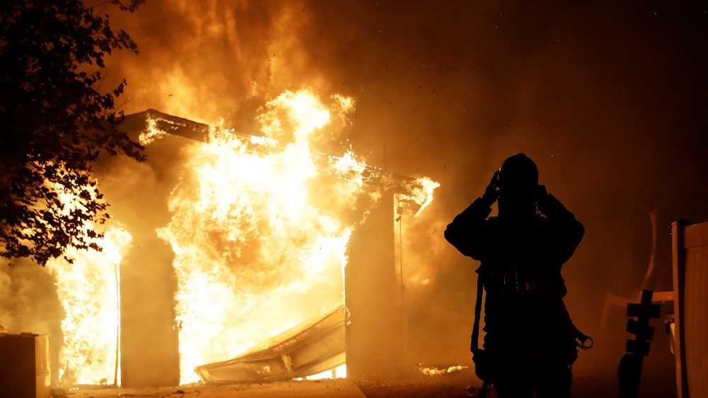 A firefighter prepares to fight a wildfire as it overtakes a home in Santa Clarita, California