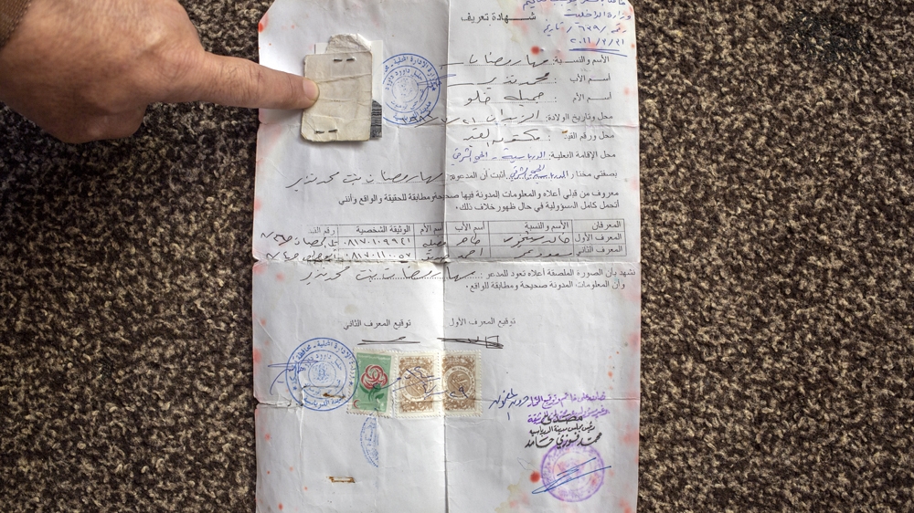 Abu Mohammed points at his wife's Syrian identification papers, which is often given to those without citizenship