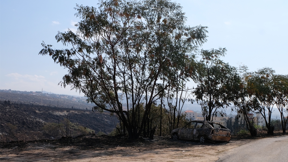 A burned-out car sits about 100 metres down the road from Mona Khoury’s house