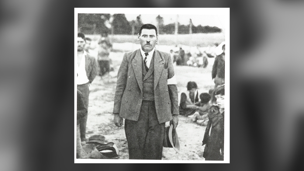 Photograph of a Roma man, thought to be Jozef Kwiek, Belzec, in German-occupied Poland, 1940. Romani families in the background [Wiener Holocaust Library Collections]