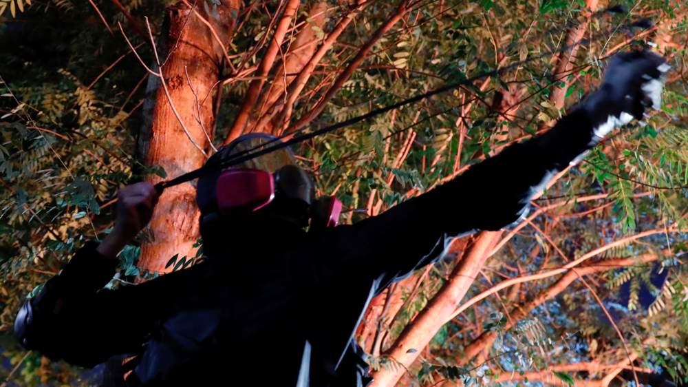 An anti-government demonstrator uses a slingshot during fighting with riot police