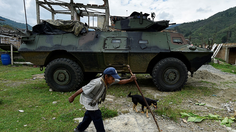 An indigenous woman walks next to a Colombian Army armoured vehicle in Toribio, department of Cauca, Colombia
