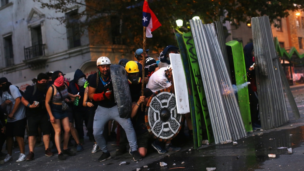 Demonstrators take cover behind improvised barricades during a protest against Chile’s government in Santiago
