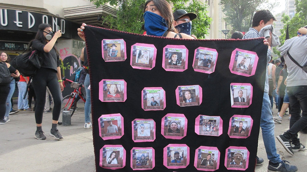 At a protest Monday in Santiago, indigenous Mapuche university student Cristina Paillal displays images of the more than 20 people killed during the ongoing unrest