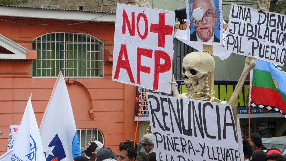 A protester carries a skeleton at a march in northern Chile, with a sign calling for the resignation of president Sebastian Pinera