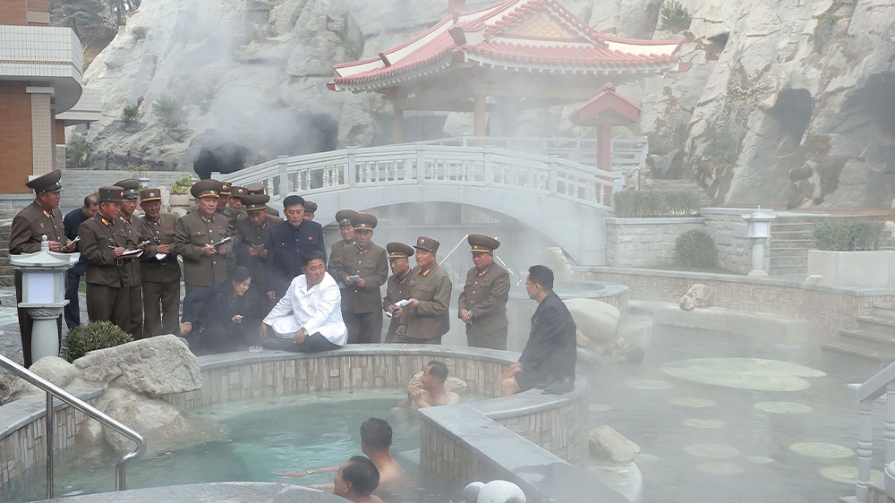 North Korean leader Kim Jong Un chats with men sitting in a hot tub at the Yangdok County Hot Spring Resort [KCNA via Reuters]