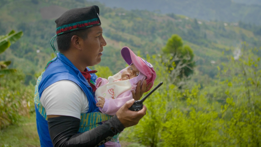 A coordinator of the Indigenous Guard holds his infant daughter during a territorial control survey in Tacueyo, Cauca