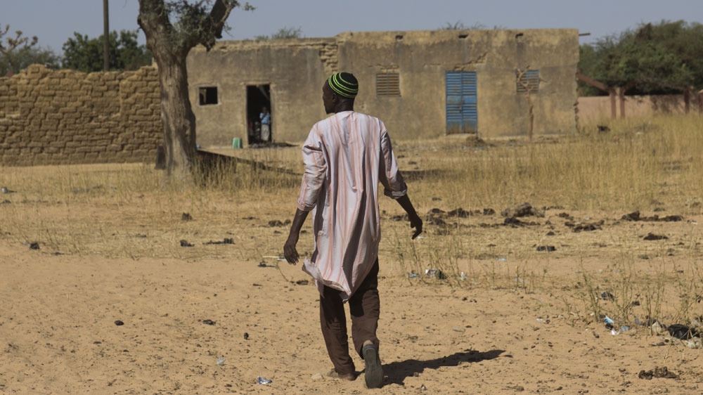 A refugee in Dori makes his way through one of the host communities where around 90 internally displaced people live [Al Jazeera]