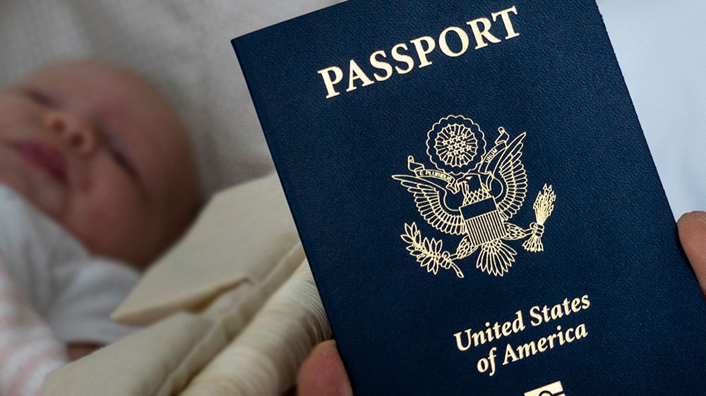 A father holds up the US passport of his child