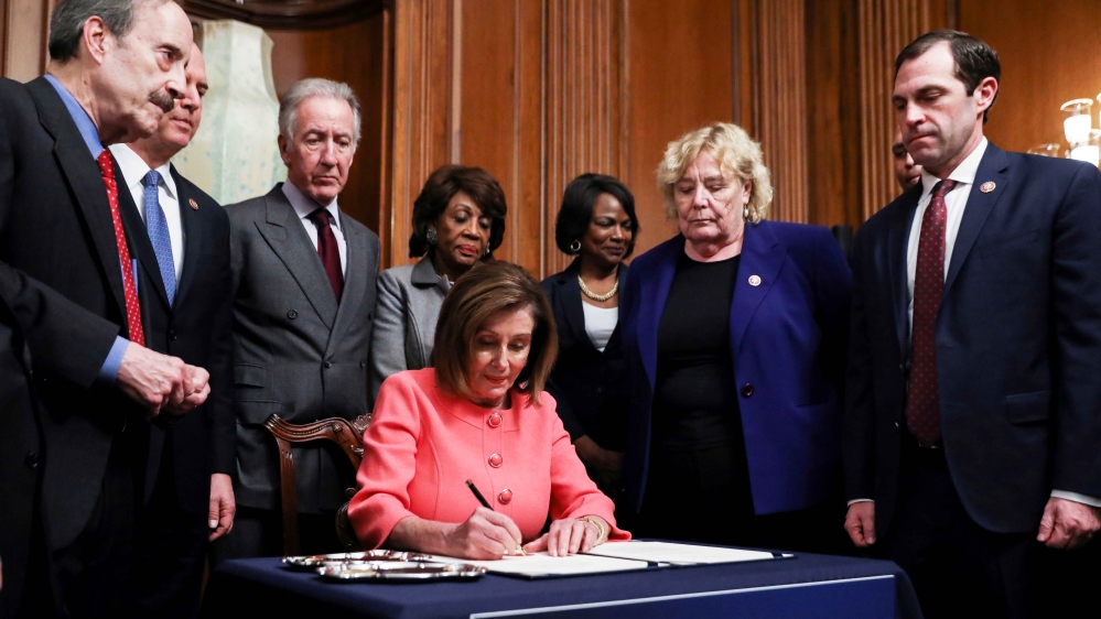Speaker of the House Nancy Pelosi, a Democrat, is surrounded by the House impeachment managers and committee chairs as she signs the two articles of impeachment for US President Donald Trump before sending them to the Senate during an engrossment ceremony