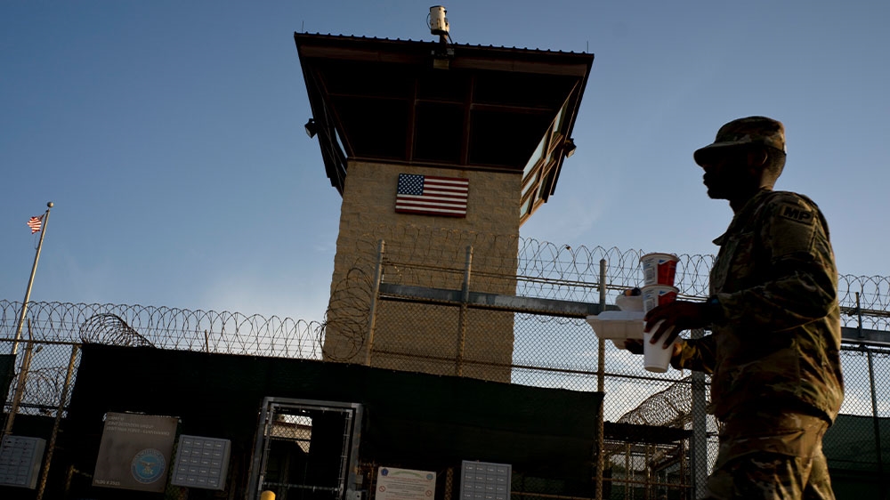 Taskforce member walking past the Camp VI detention facility at the Guantanamo Bay US Naval Base, Cuba