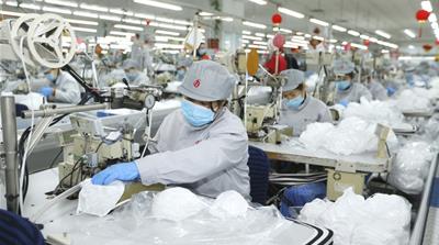 In this photo released by Xinhua News Agency, workers produce face masks in the workshop of a textile company in Jimo District of Qingdao in eastern China's Shandong Province on Wednesday, Feb. 12, 20