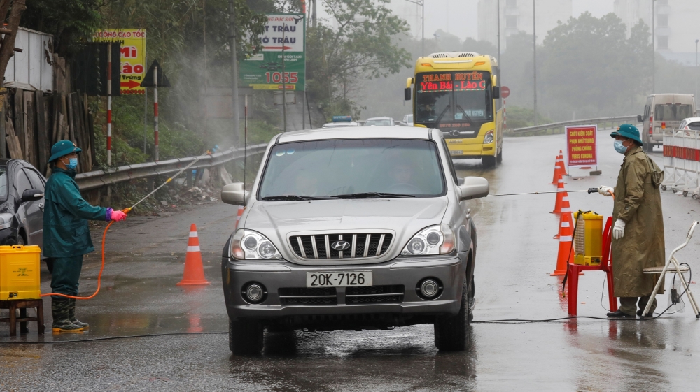 Members of anti-coronavirus team spray chemical onto vehicles on a road in Thai Nguyen province earlier this month