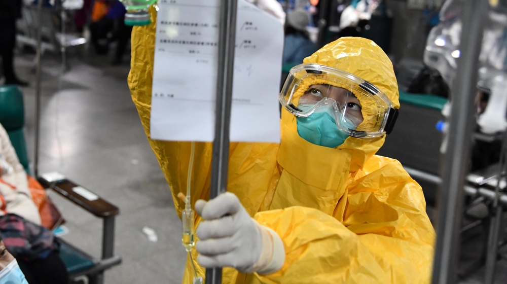 A medical worker in protective suit adjusts a drip bag for a patient at a hospital in Wuhan, Hubei province, China, February 3. China Daily via REUTERS