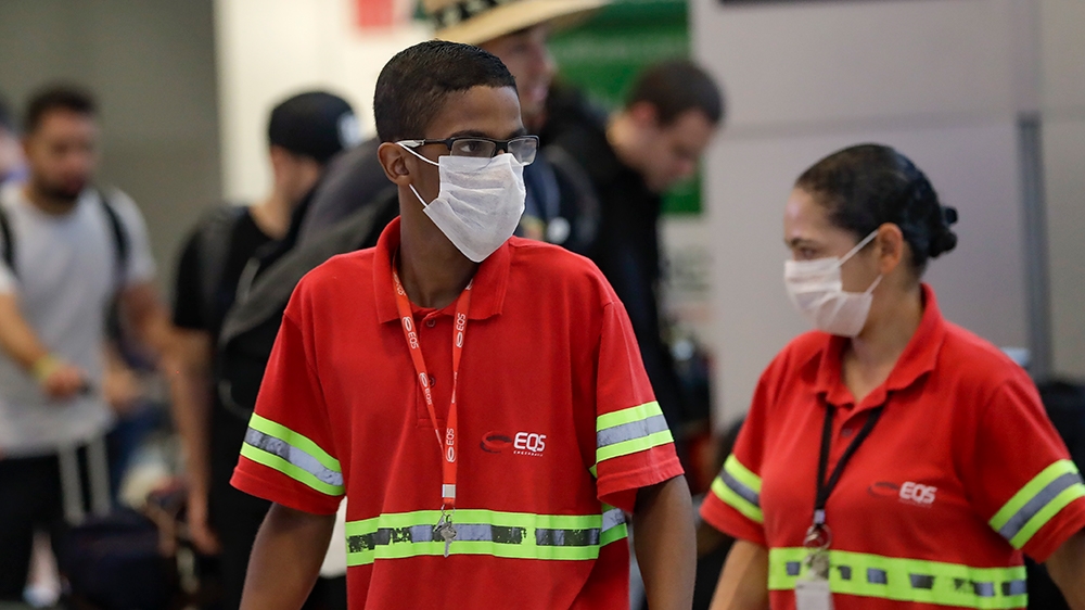 Airport employees wear masks as a precaution against the spread of the new coronavirus COVID-19 as they work at the Sao Paulo International Airport in Sao Paulo, Brazil, Wednesday, Feb. 26, 2020. (AP