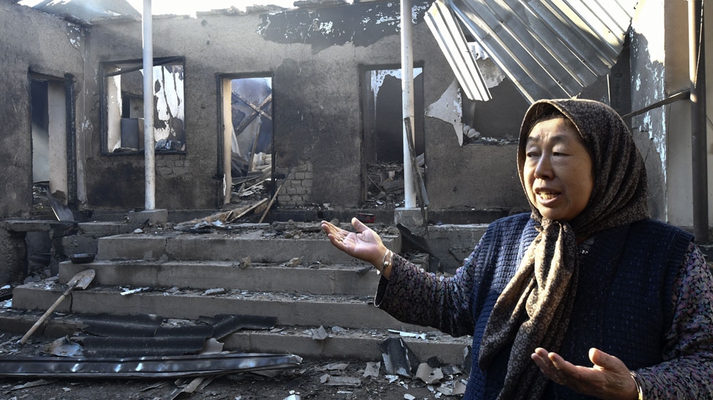 A local resident shows her burned house after the conflict in Shor-Tube