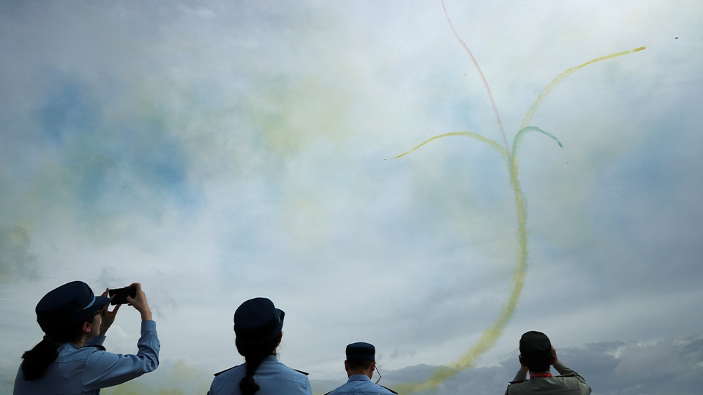 Members of China’s People’s Liberation Army Air Force (PLAAF) watch an aerial display by the Ba Yi Aerobatics team during a media preview of the Singapore Airshow