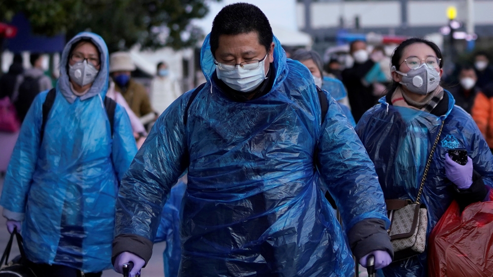 People wear face masks and plastic raincoats as a protection from coronavirus at Shanghai railway station, in Shanghai, China.