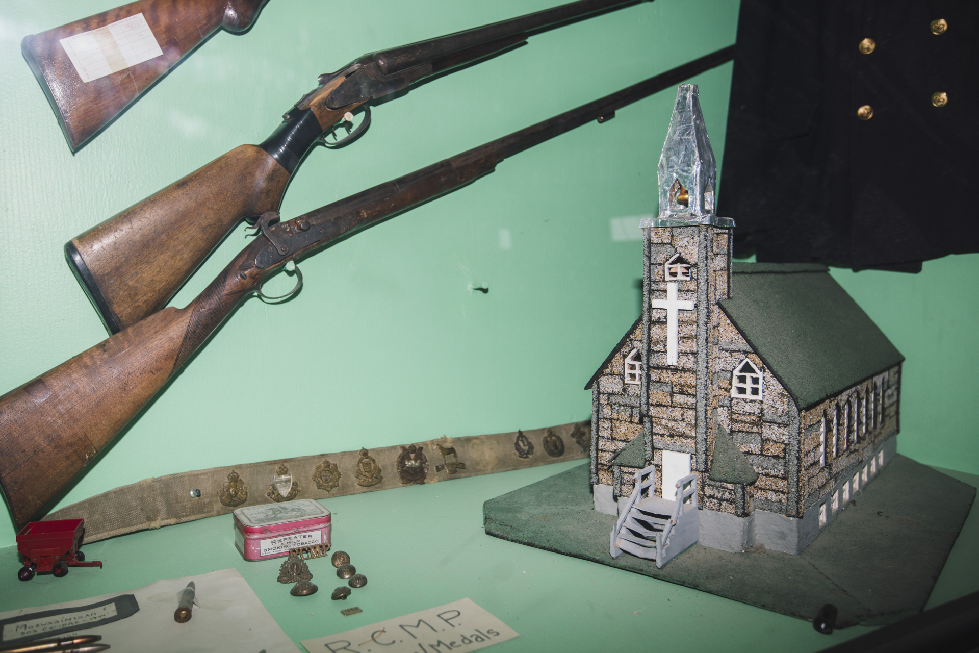 A museum display shows RCMP memorabilia and a model of the catholic church where residential school students would be picked up by trucks