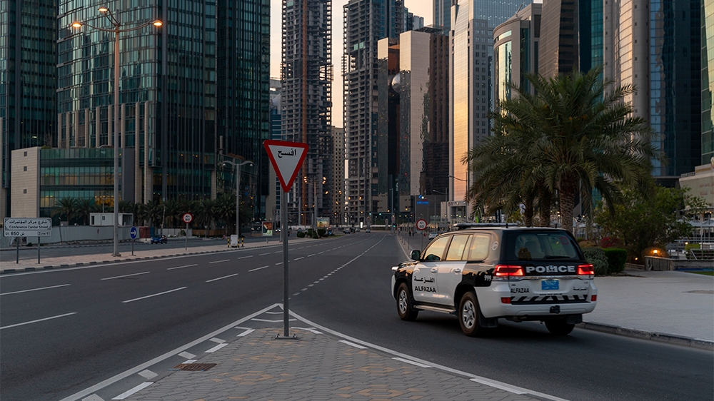 A police car patrols an almost empty road in West Bay area in Doha, Qatar, March 25, 2020. Qatar has imposed a series of measures to contain the coronavirus outbreak, including closing of parks and pu