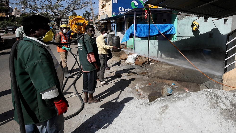 Workers in Bangalore spray disinfectant on a road during the nation-wide lockdown