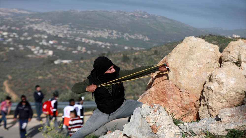 A Palestinian uses a slingshot to hurl stones at Israeli security forces near the town of Beita