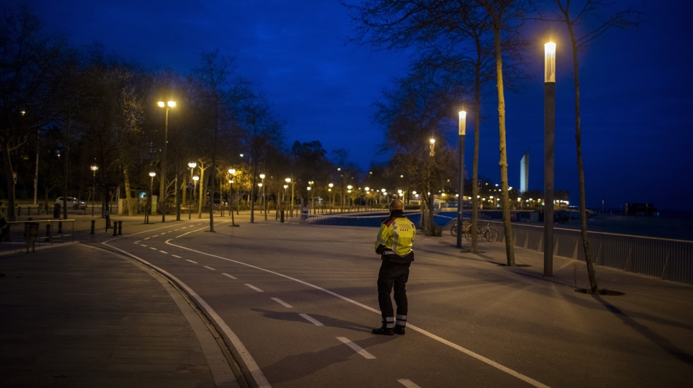A Catalan police officer stands guard in an empty promenade in Barcelona, Spain, Saturday, March 28, 2020. Spanish Prime Minister Pedro Sánchez has announced that his government will order a two-week