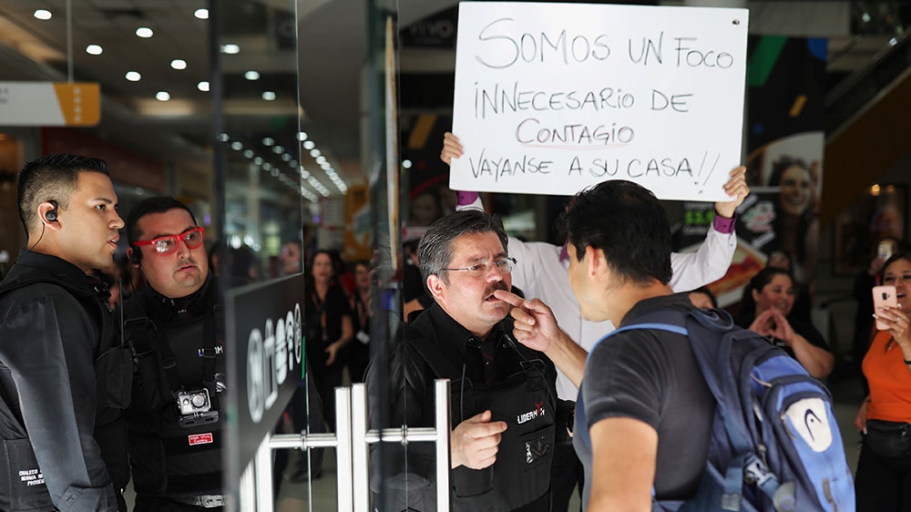 Mall workers protest with a banner reading, ‘We are an unnecessary source of infection, Go home’ while a customer tries to access a store during the outbreak of coronavirus disease (COVID-19) in Santiago, Chile