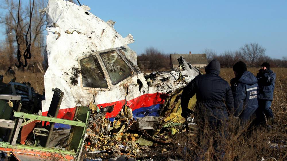 Local workers transport a piece of wreckage from Malaysia Airlines flight MH17 at the crash site