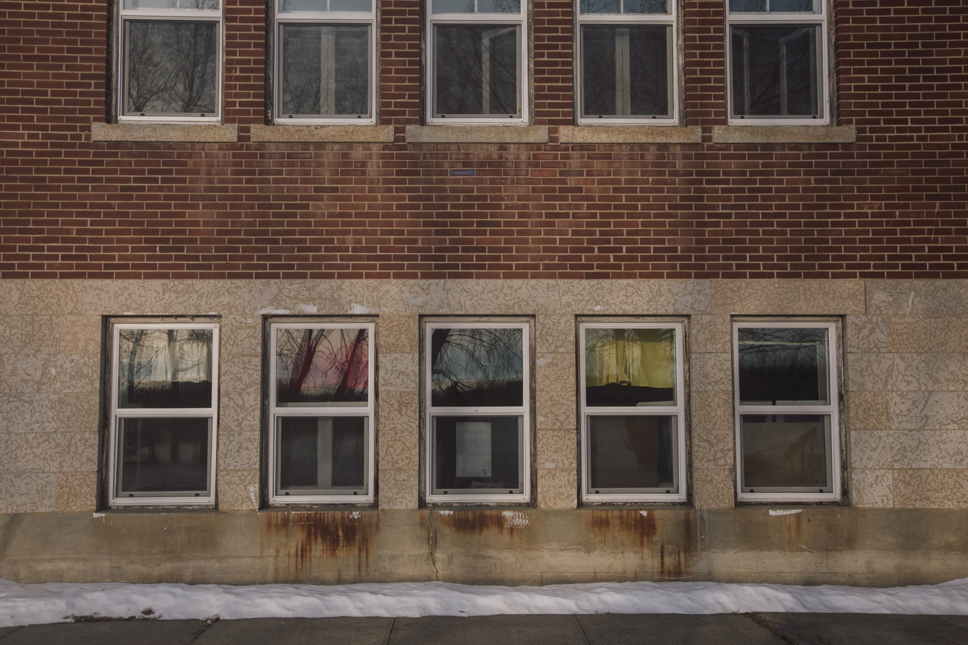 Curtains reflecting the colours of the medicine wheel – white, red, black and yellow – hang in the windows of the former residential school