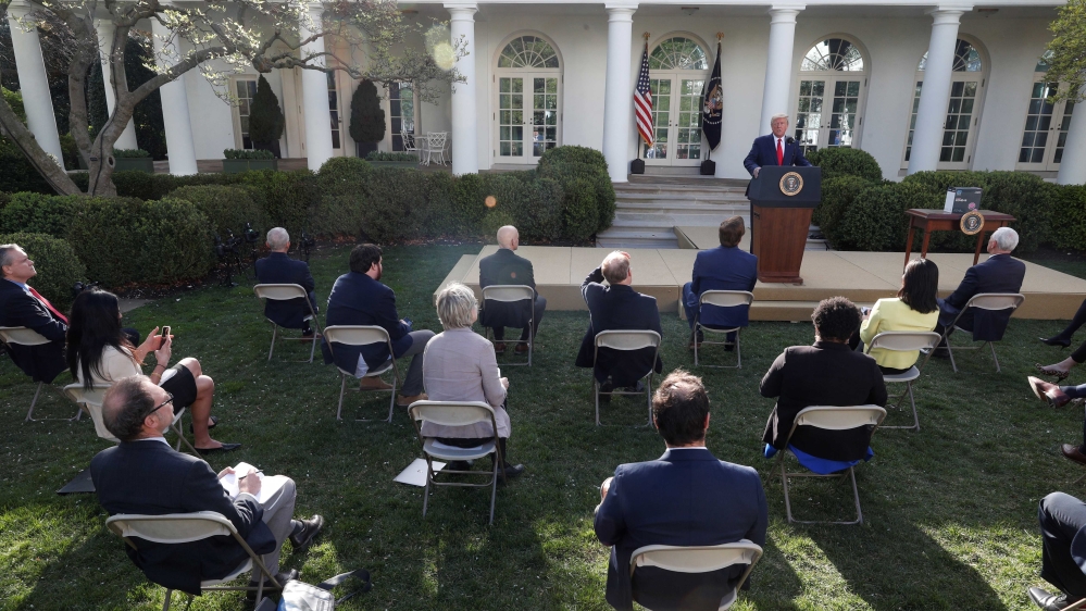Reporters sitting at a distance from each other listening to US President Donald Trump as he addresses the daily coronavirus response briefing in the Rose Garden at the White House in Washington, US