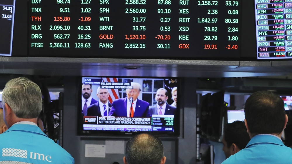 Traders watch US President Trump on the monitor on the floor of the New York Stock Exchange (NYSE) in New York