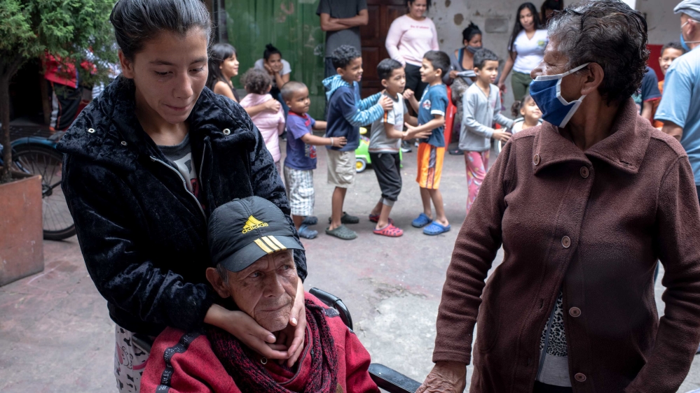 Daniela Castano and her grandfather are seen outside their home, where they live in close quarters with several other families