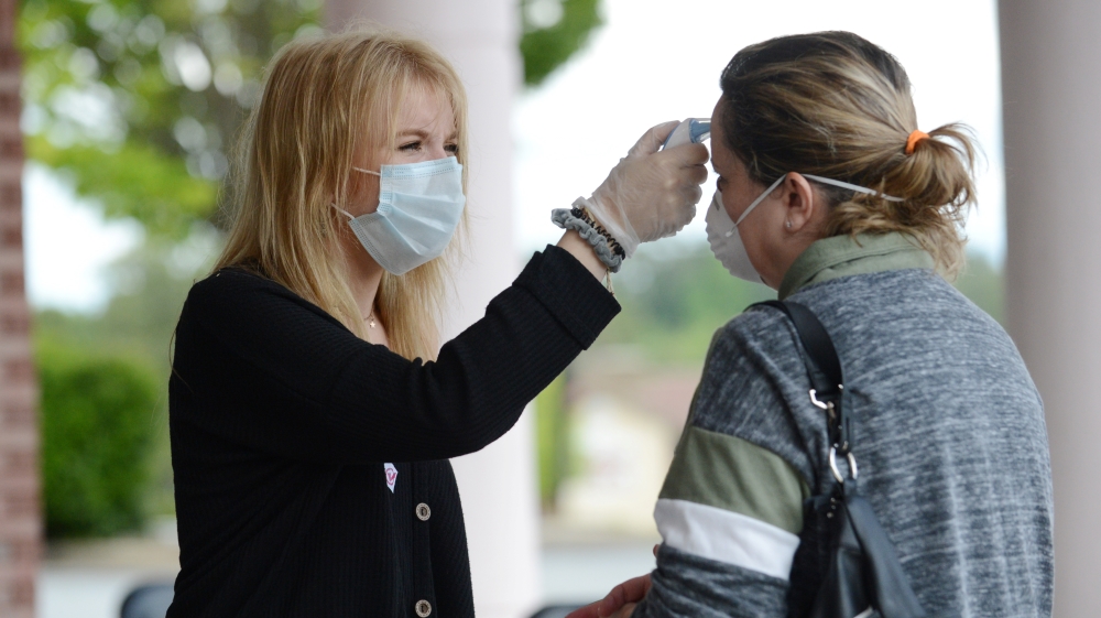 Alexandra Homyak takes a customer’s temperature before she enters Three-13 Salon, Spa and Boutique, during the phased reopening of businesses and restaurants in Georgia