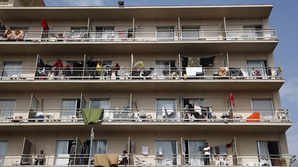 Refugees gather on their balconies at the hotel in Kranidi, which hosts about 450 asylum seekers and was placed in isolation on Monday after a pregnant resident tested positive for the new coronavirus during a hospital visit