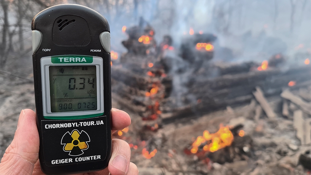 A Geiger counter shows increased radiation levels against the background of the forest fire.